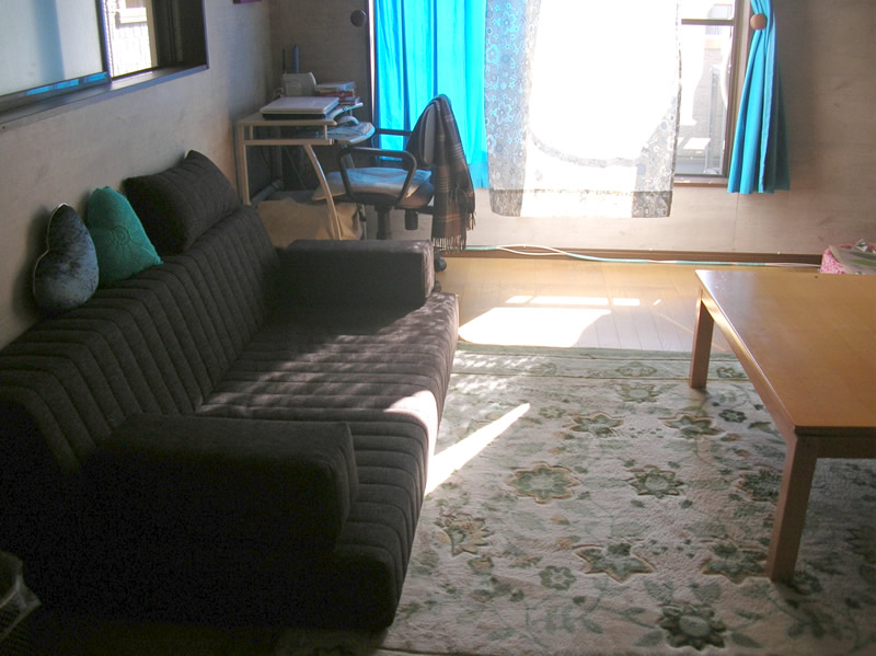 ブラウンのつみきソファーでシックなお部屋に。カーテンとクッションのブルーが良く映えます